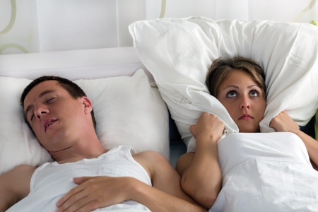 Snoring man and young woman, couple sleeping in bedの写真素材