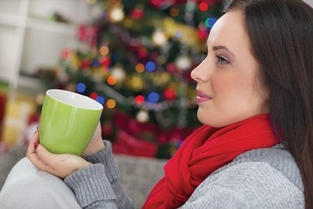 women in Christmas night drinking hot tea, in the background Christmas treeの写真素材