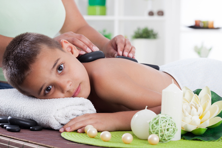 therapist massaging a young boy in the spa salonの写真素材