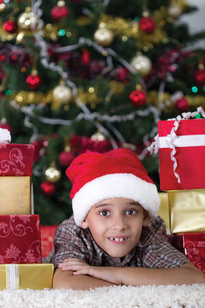 Happy little boy smiling with gift box near the Christmas tree.の写真素材