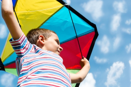 Boy with bright kite over the head on the blue sky view の写真素材