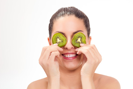 healthy woman placing half kiwi front of eyesの写真素材