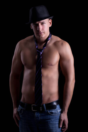 a muscular man posing in a tie with a hat,on black backgroundの写真素材