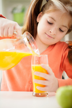 A little girl drinking a juice at home の写真素材