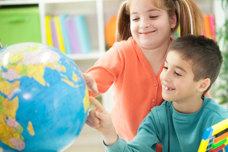 young brother sister shows place on the globe, together teach geographyの写真素材
