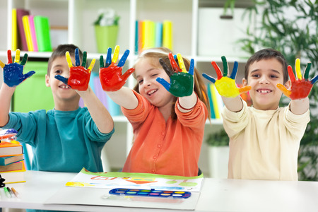 Three happy little  kids with painted hands playing at home and drawの写真素材
