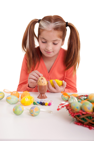 Beautiful girl  with pigtails painting easter eggsの写真素材