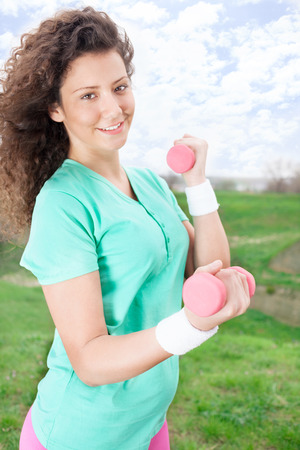 Portrait of Beautiful young woman exercising with weights in the park  の写真素材