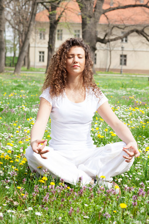 Young girl in lotus pose in the park の写真素材
