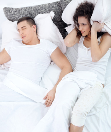 Young couple in bed woman trying to sleep while a man is snoringの写真素材
