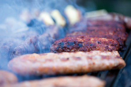 pork and beef sausages cooking over the hot coals on a barbecue fire, close up  viewの写真素材