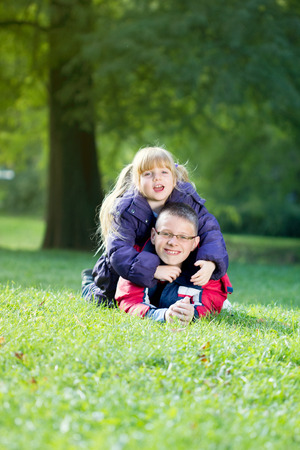 sister and brother together in the park lying on green grassの写真素材