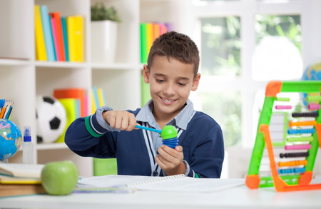 smiling schoolboy siting at the desk in home and sharp pencilの写真素材