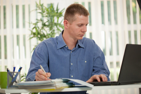 Handsome businessman working with laptop in officeの写真素材