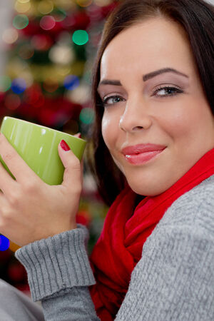 women in Christmas night drinking hot tea, in the background Christmas tree の写真素材