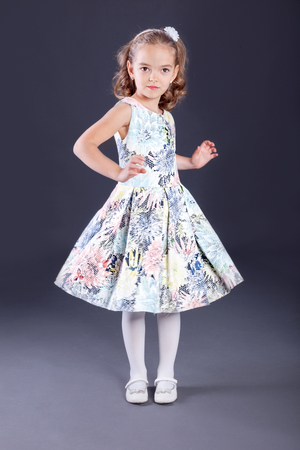 little girl in luxurious dress on gray backgroundの写真素材