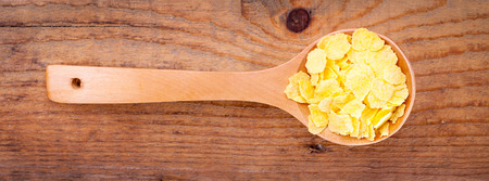 cornflakes in wooden spoon,on wooden backgroundの写真素材