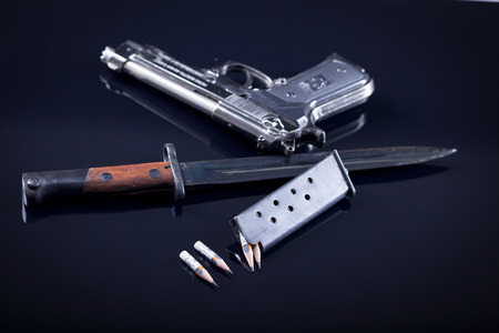magazine knife, pen in the form of bullet and blurred gun in the backgroundの写真素材