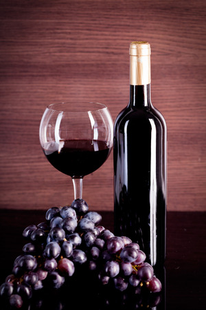 bottle with red wine and glass and grapesの写真素材