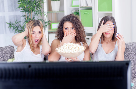 group of young women sitting on couch watching sad movie depressedの写真素材