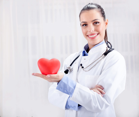 healthcare and medicine concept - smiling female doctor with heart and stethoscopeの写真素材
