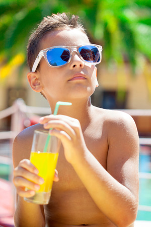 Portrait of young boy wearing sunglasses relaxing on beach.の写真素材