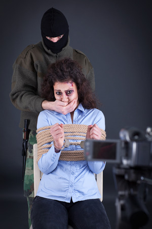 kidnapped beaten girl tied with rope and handcuffs in the hands of terroristsの写真素材