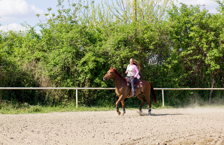 young smiling girl riding her brown horseの写真素材