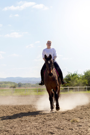 smiling blonde woman riding her brown horseの写真素材