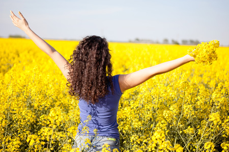 Attractive woman with outstretched arms in rapeseed field in summerの写真素材