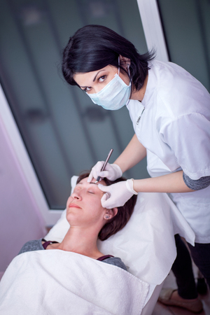 Cosmetologist applying permanent make up on eyebrowsの写真素材