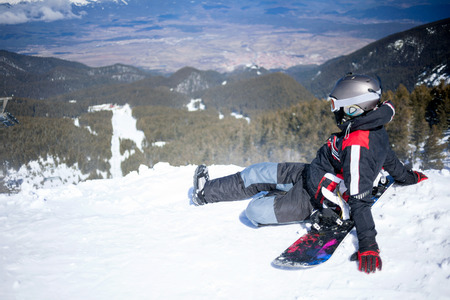snowboarder sitting against the beautiful view of the mountainsの写真素材