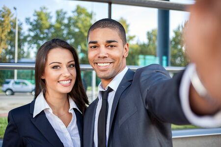 business people taking selfie and looking at mobile phoneの写真素材