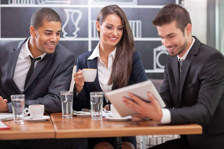 Business people looking at digital tablet in cafffee during a meetingの写真素材