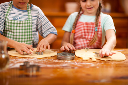 Two beautiful caucasian child making a cake, smiling happily,の写真素材