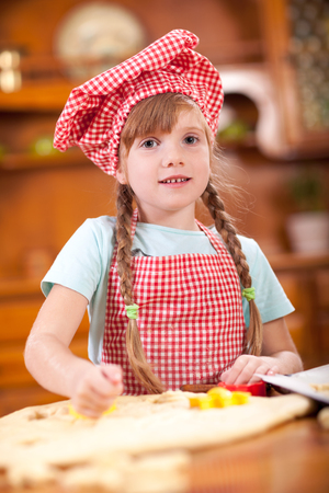 little girl kneading a dough to make cakes in the kitchenの写真素材