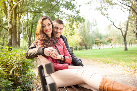 Young romantic couple on a bench in park. Autumn setの写真素材