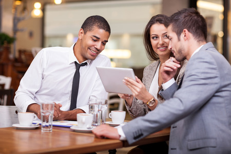 Three young businessman on a break at the restaurant, discuss new ideas and projectsの写真素材