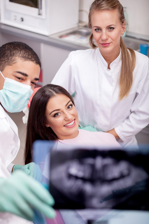 Dentist team and patient looking at x-ray imageの写真素材