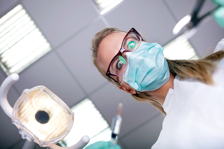 scary and funny dentist working with a patient in protective work wearの写真素材