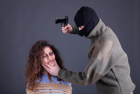 terrorists holding a gun and threatens womanの写真素材