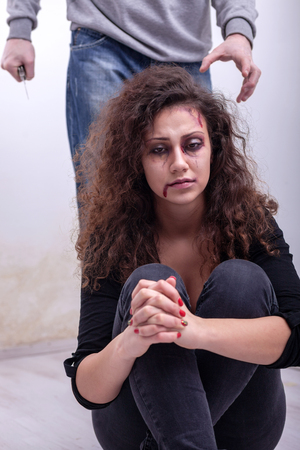 Husband holding a knife intimidates his wifeの写真素材