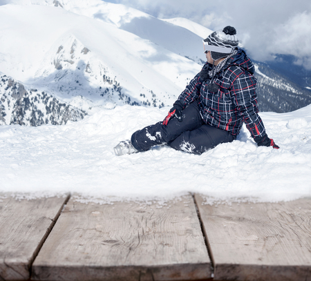 woman sitting on the snow and looking on mountainの写真素材