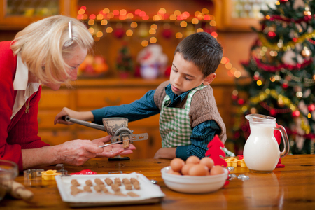 grandmother and little boy baking Christmas cakes in the kitchenの写真素材