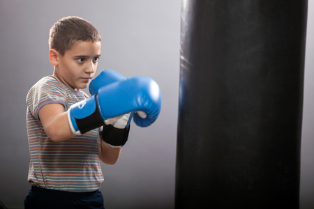 serious young boxer with blue gloves hitting the bagの写真素材
