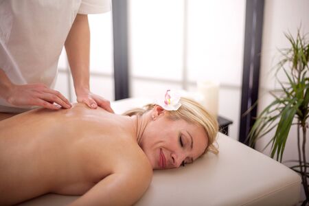 professional masseur doing massage of female back in the beauty salonの写真素材