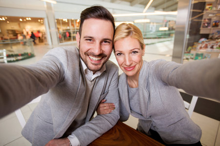 technology, photographing, and people concept - happy couple taking selfie with smartphone or camera...