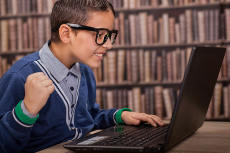 surprised young  boy in the library with computerの写真素材