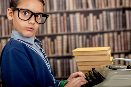 surprised young  boy in the library with typewriterの写真素材