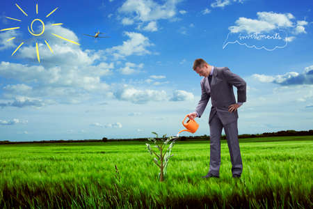 businessman watering tree with money and waiting to grow investmentsの写真素材
